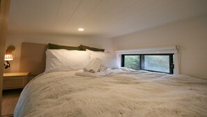 Une chambre avec un grand lit, une fenêtre donnant sur un beau paysage et une lampe de chevet.