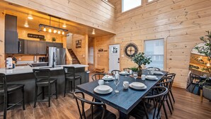 Une cabane en bois comprenant une cuisine, un coin repas et un escalier menant à un étage supérieur.