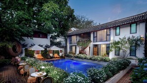 Ein modernes Haus mit Swimmingpool, Sitzgelegenheiten im Freien und einem Garten.