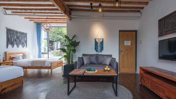 A cozy room with a wooden ceiling, a bed, a sofa, a coffee table with fruit, and a TV on the wall.