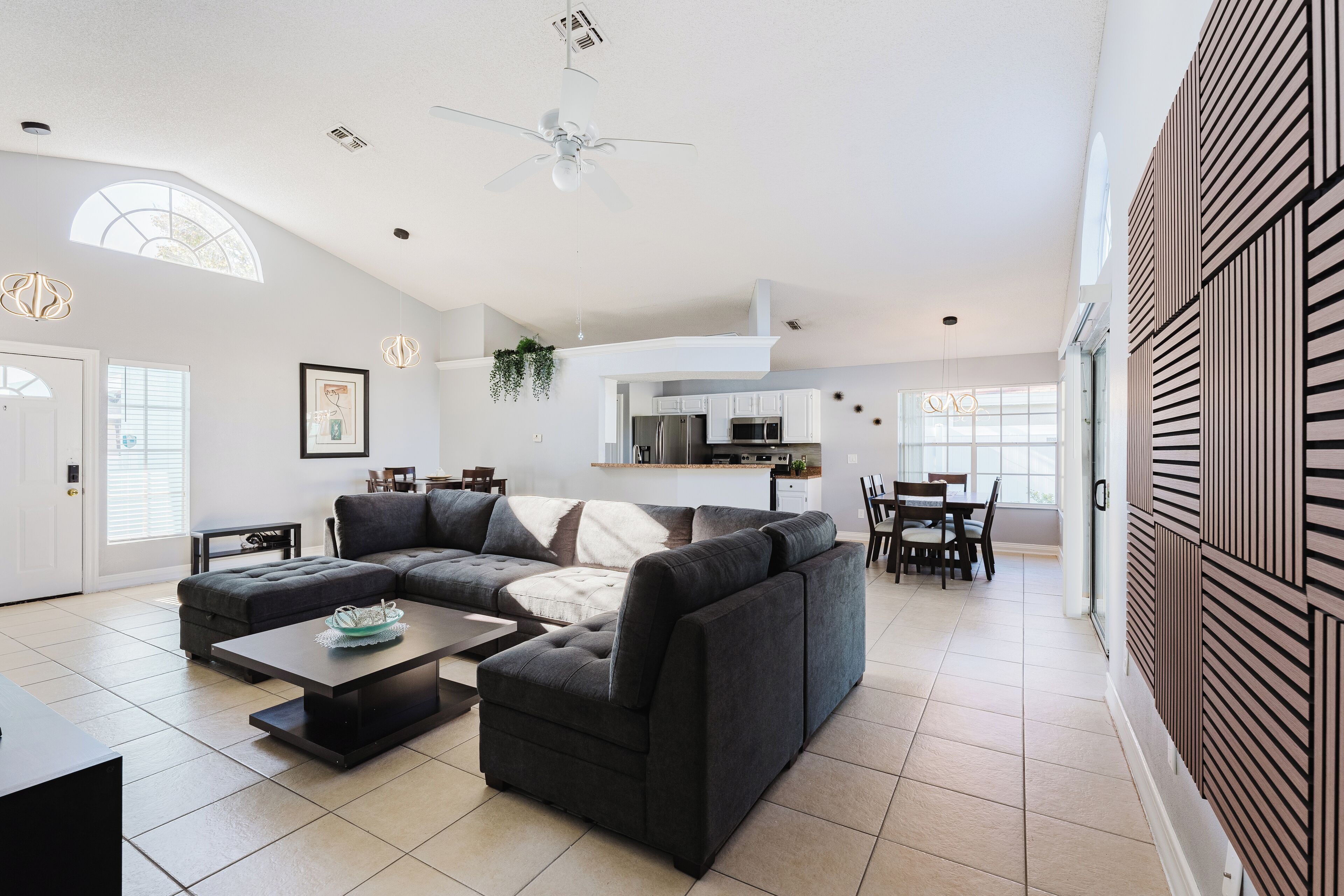 A modern living room with a sectional sofa, a coffee table, and a dining area with a table and chairs.