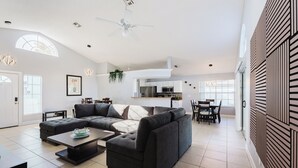A modern living room with a sectional sofa, a coffee table, and a dining area with a table and chairs.