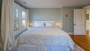 Une chambre à coucher avec un lit, une fenêtre avec des rideaux, une porte et un luminaire fixé au mur.