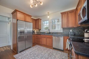 A modern kitchen with wooden cabinets, stainless steel appliances, and a patterned rug. - Monthly Rental 5 Minutes to Downtown! (Brevard)