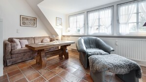 A cozy living room with a wooden table, a leather armchair, and a sofa. - Green Teft, Whg. 8 - Green Teft - thatched house in the southwest part of the village (Sylt / OT Keitum)