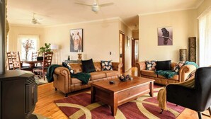 A living room with two leather sofas, a wooden coffee table, and a dining area with a table and chairs.