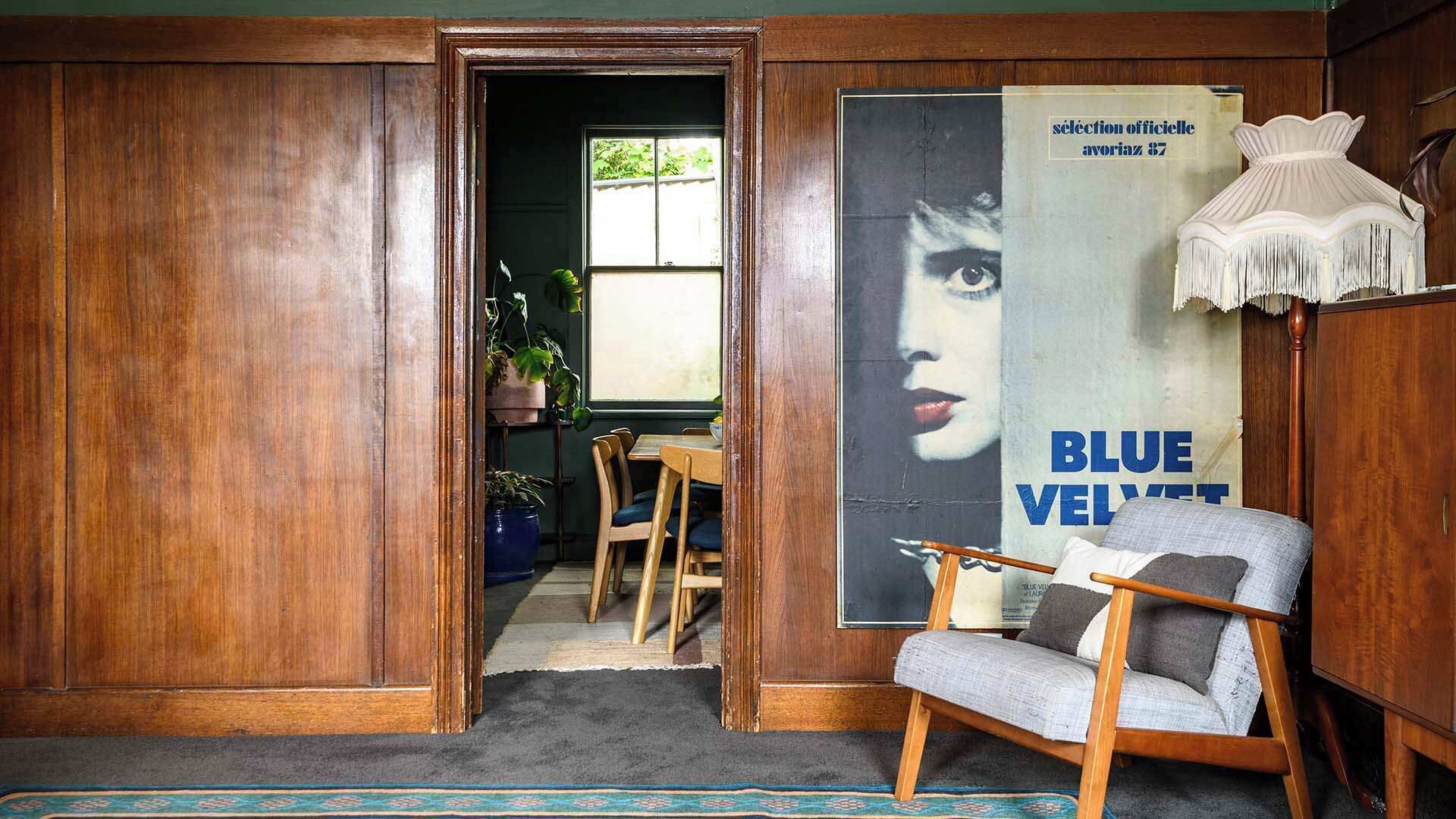 Une pièce avec une porte en bois, un coin repas comprenant une table et des chaises, et une affiche accrochée au mur.