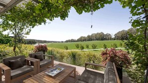 Une terrasse dotée de mobilier d’extérieur, offrant une vue sur un terrain de golf.