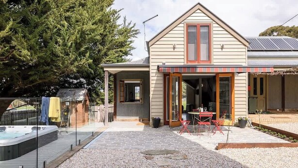 A two-story house with a covered patio, a hot tub, and a fenced yard.
