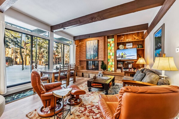 A spacious living room with a fireplace, large windows, and a cozy seating area.