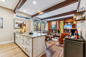 A modern kitchen with a central island, wooden beams, and a fireplace. - Breckenridge Condo Steps from Main Street & Peak 9 (Breckenridge)