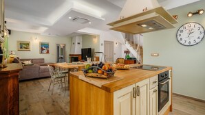 Un vaste espace de vie comprenant une salle à manger avec une table en bois, un canapé et une cuisine dotée d’un îlot central.
