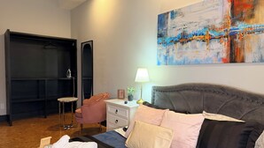 Ein Schlafzimmer mit Bett, Nachttisch, Lampe, Stuhl, Kleiderschrank und einem Bild an der Wand.