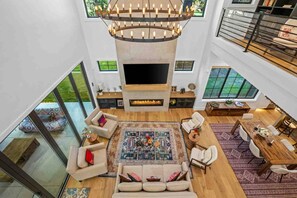 A spacious living area with a fireplace, a large rug, and a high ceiling with a unique chandelier. - Maison Ananda | Gated 5BR Luxury Estate in Lake Oswego, Sleeps 12 (Lake Oswego)
