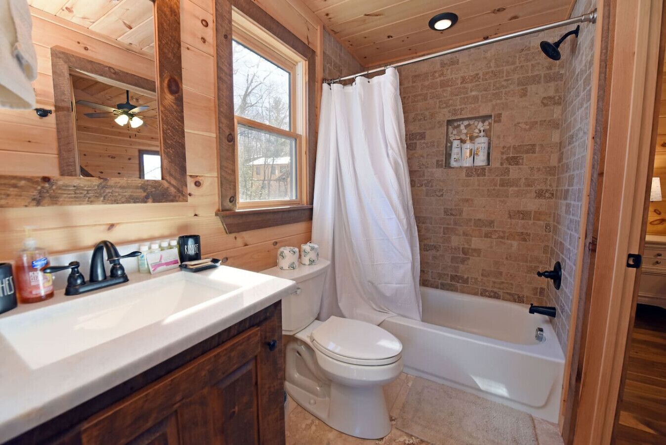 A bathroom with a wooden interior, a white toilet, a bathtub, and a shower curtain.