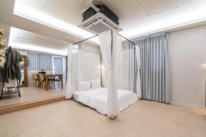 A modern bedroom with a canopy bed, a dining area, and a large window with curtains. - From H Dongbaek Hotel By Kwon Geoje Gohyeon (Geoje)