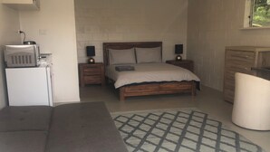 A bedroom with a bed, bedside tables, a small desk, a chair, and a rug.