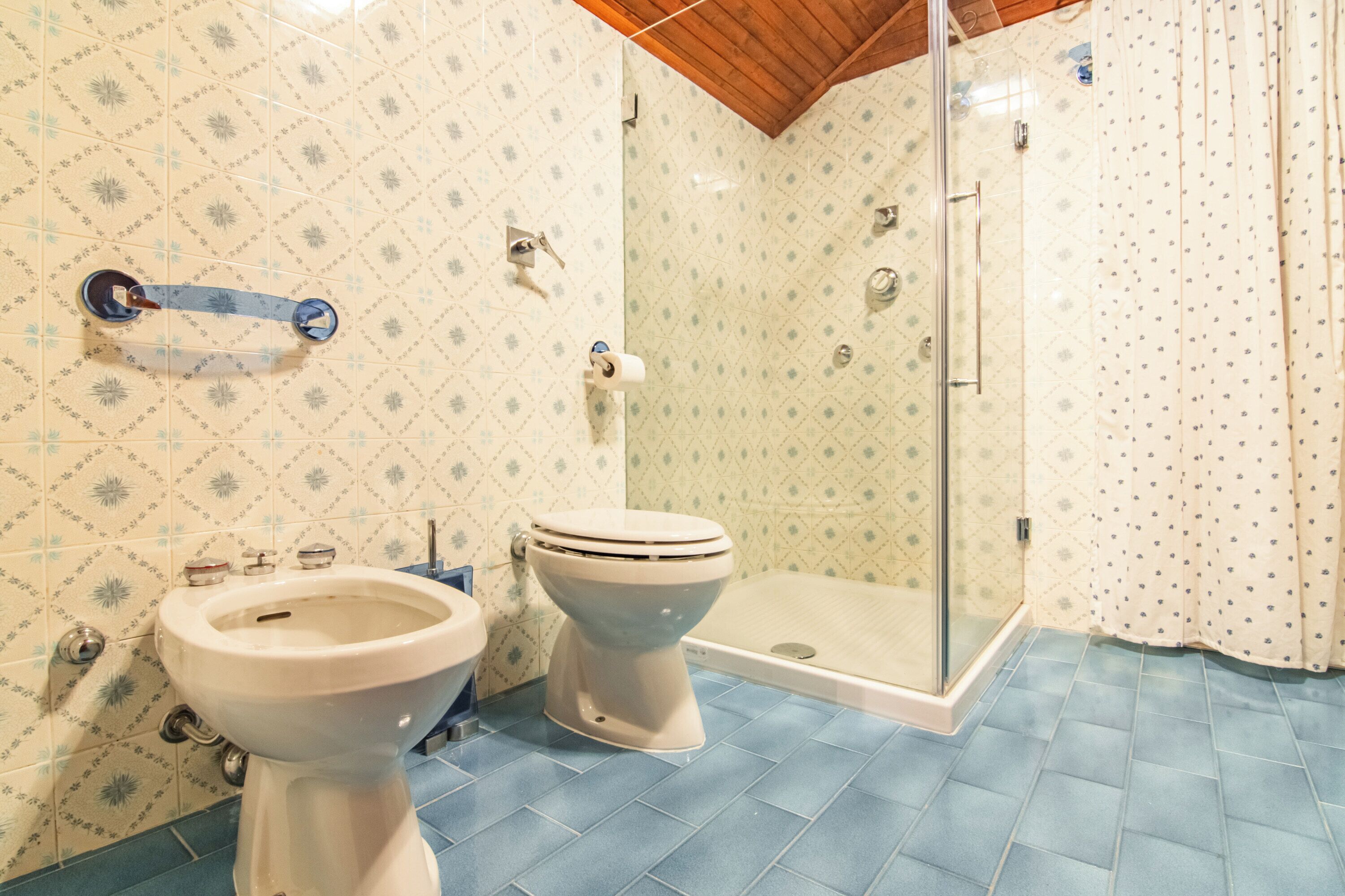 A bathroom with a shower, two toilets, and a sink.