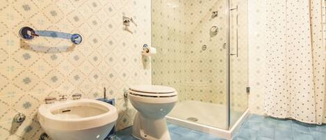 A bathroom with a shower, two toilets, and a sink.