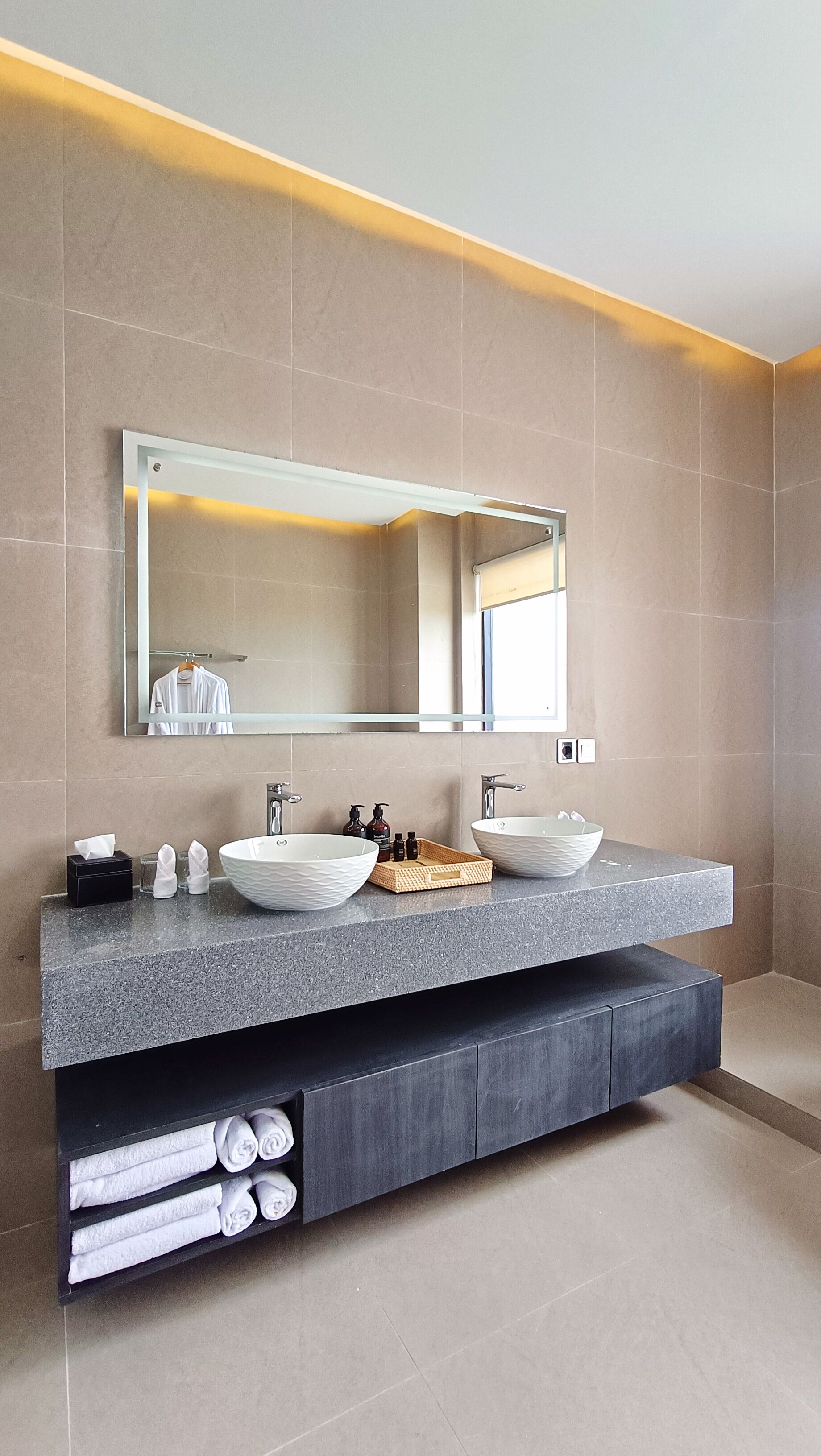 Une salle de bain moderne avec un grand miroir, deux lavabos et un porte-serviettes.