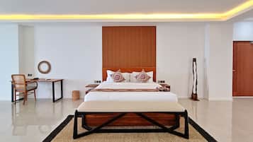 A modern bedroom with a large bed, bedside tables, a chair, a desk, and a wooden headboard.
