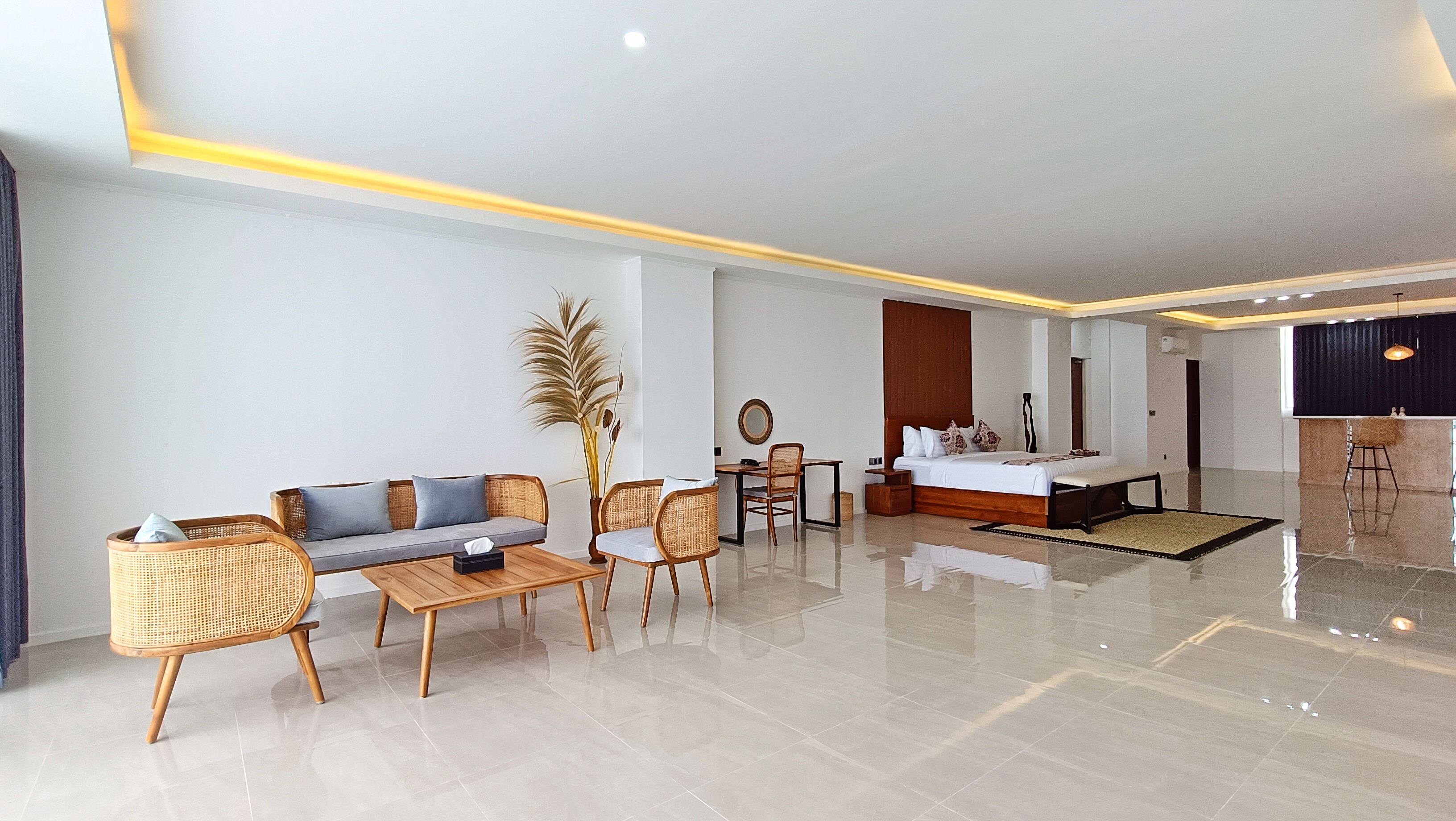 Ein modernes Hotelzimmer mit Sofa, Esstisch, Stühlen, einem Bett und einer kleinen Küchenzeile.