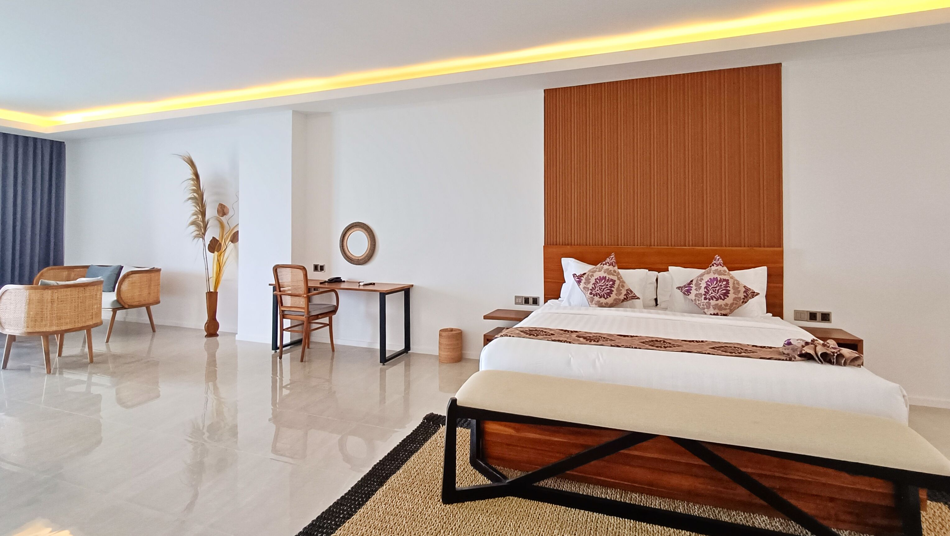 A modern hotel room with a large bed, a desk, a chair, and a small table.