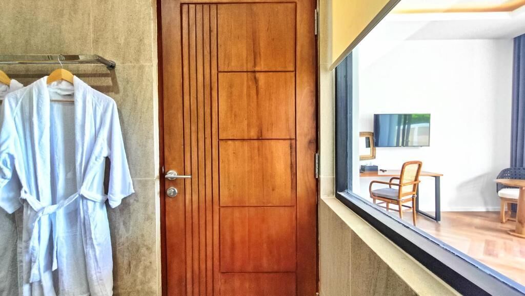 A wooden door with a view of a room with a TV, a chair, and a table.