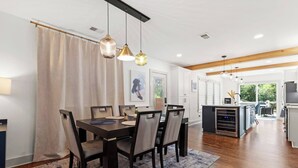 A modern kitchen with a central island, wooden flooring, and pendant lighting.