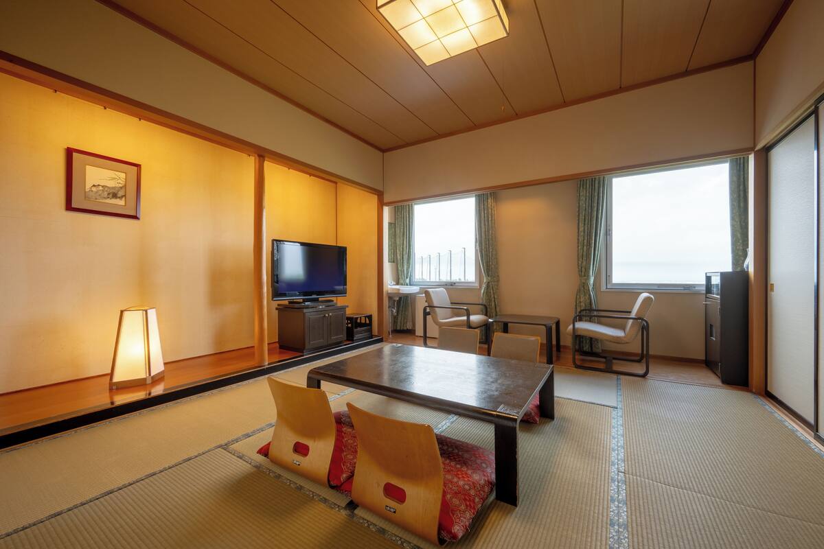 Una habitación de estilo japonés tradicional con suelo de tatami, una mesa baja y asientos.