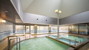 Una piscina interior con múltiples pistas, barandales de metal y un techo alto con iluminación empotrada.
