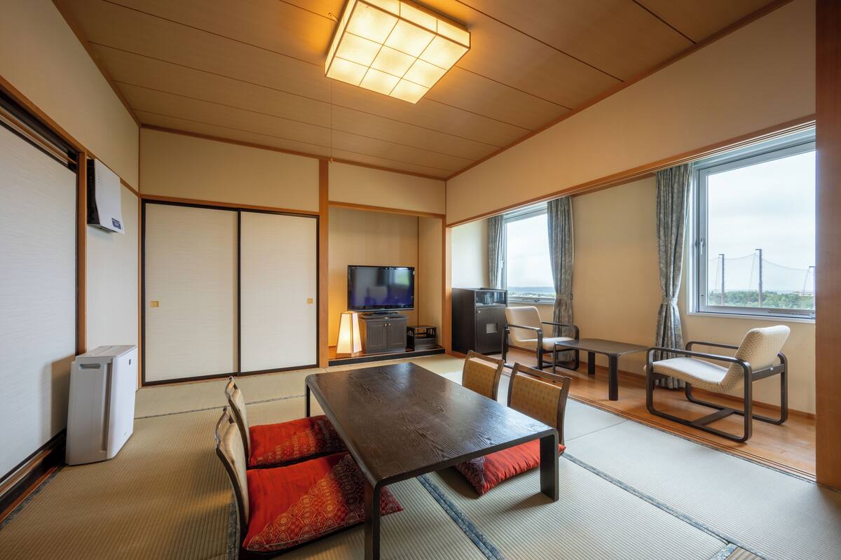 Una habitación japonesa tradicional con suelo de tatami, una mesa baja y asientos.