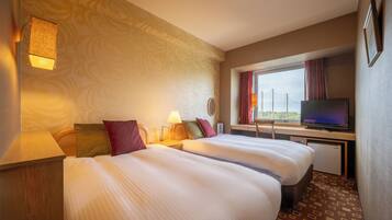 A hotel room with two beds, a television, a desk, and a window with curtains.