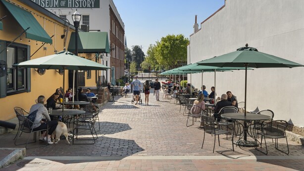 An outdoor café with tables and chairs, a dog, and people walking. - Marietta Square Suites - Suite3 - Cozy Studio! (Marietta)
