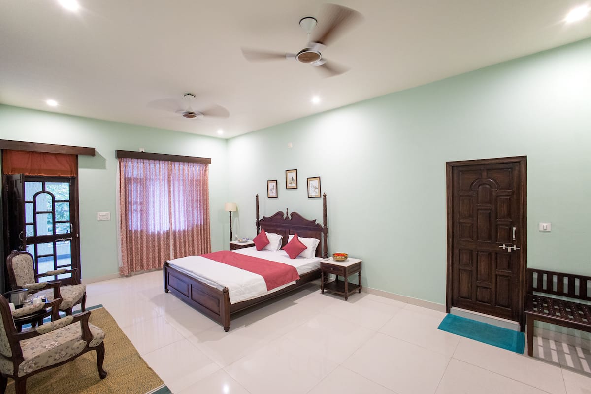 A bedroom with a bed, bedside table, chair, and a door.