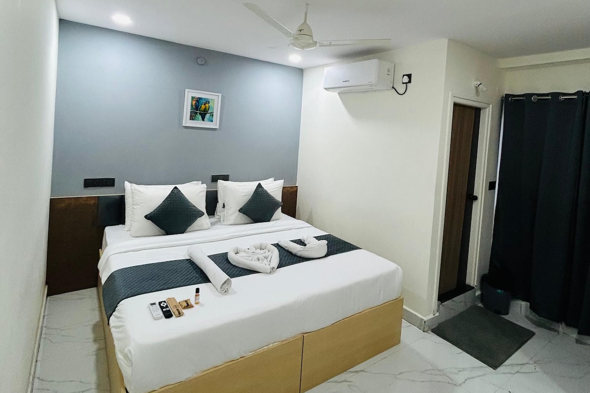 Une chambre d’hôtel moderne dotée d’un grand lit, d’un ventilateur de plafond, d’un appareil de climatisation et d’une porte donnant accès à une salle de bain.