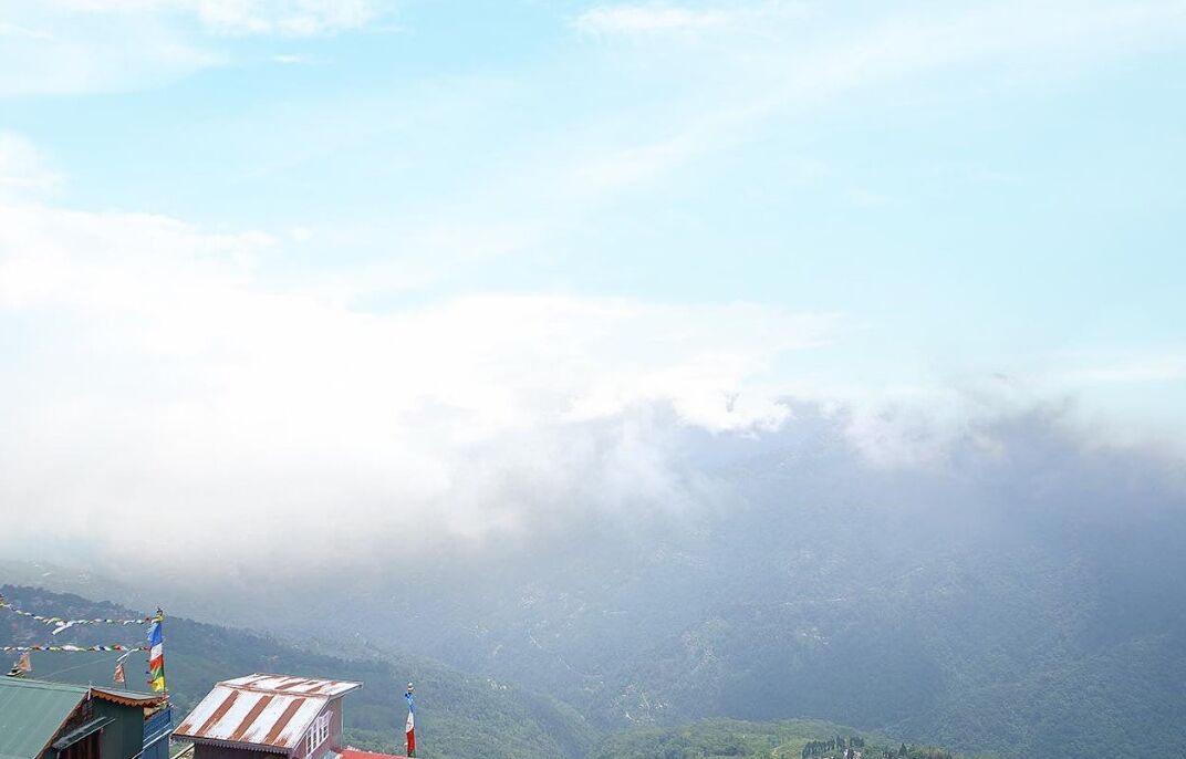 A mountainous landscape with a clear sky and a building with a flag.