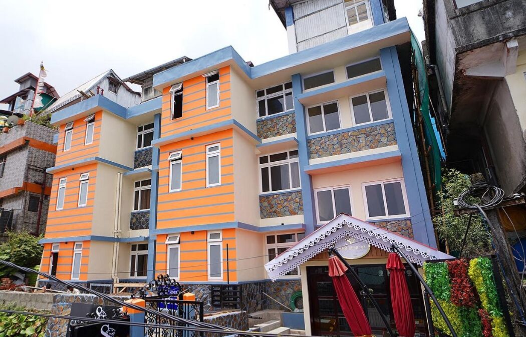 Een meerhoog gebouw met gevels in oranje en blauw, balkons en een kleine winkel met een rode luifel.