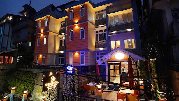 Een hotel met meerdere verdiepingen, balkons en een restaurant op de begane grond.