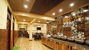 Een lange gang met houten vloeren en wanden, die uitkomt op een eetgedeelte met een buffet.