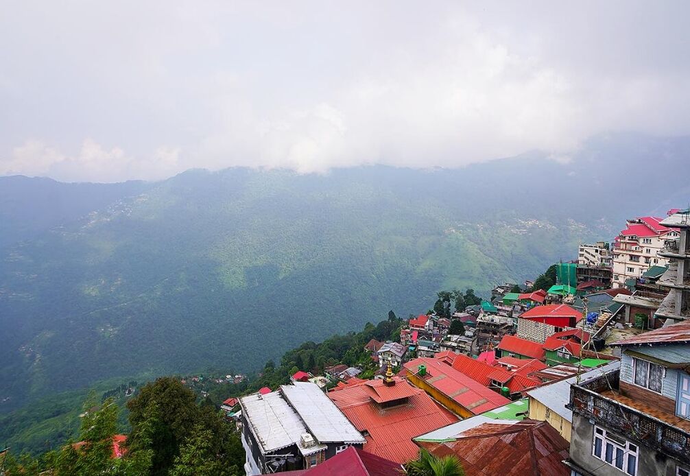 Un village de montagne aux bâtiments aux toits rouges, entouré d’une végétation luxuriante.