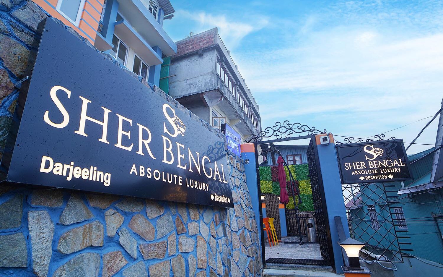 A hotel entrance with a sign reading "Sher Bengal Absolute Luxury" and "Darjeeling."
