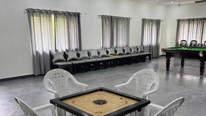 Une pièce spacieuse équipée d’une table de billard, d’un baby-foot et d’un coin salon avec des fauteuils et un canapé.