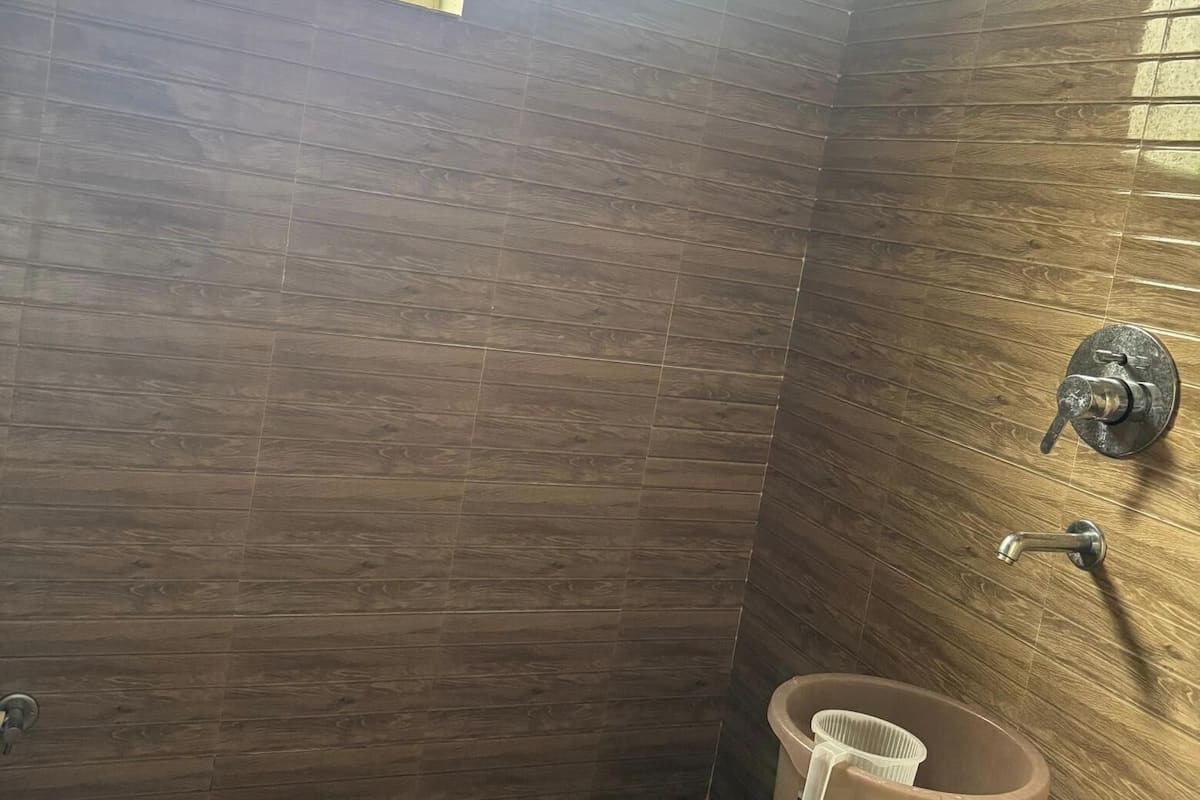 Ein Badezimmer mit Holzvertäfelung, einem Fenster, einer Dusche und einem Warmwasserbereiter.