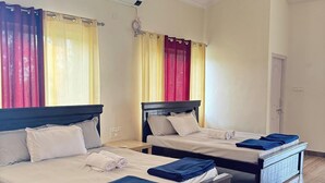 Une chambre d’hôtel avec deux lits, un plancher en bois et des ventilateurs de plafond.