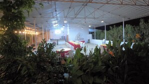 Un espace extérieur abrité, doté de tables et de chaises, et entouré de verdure.