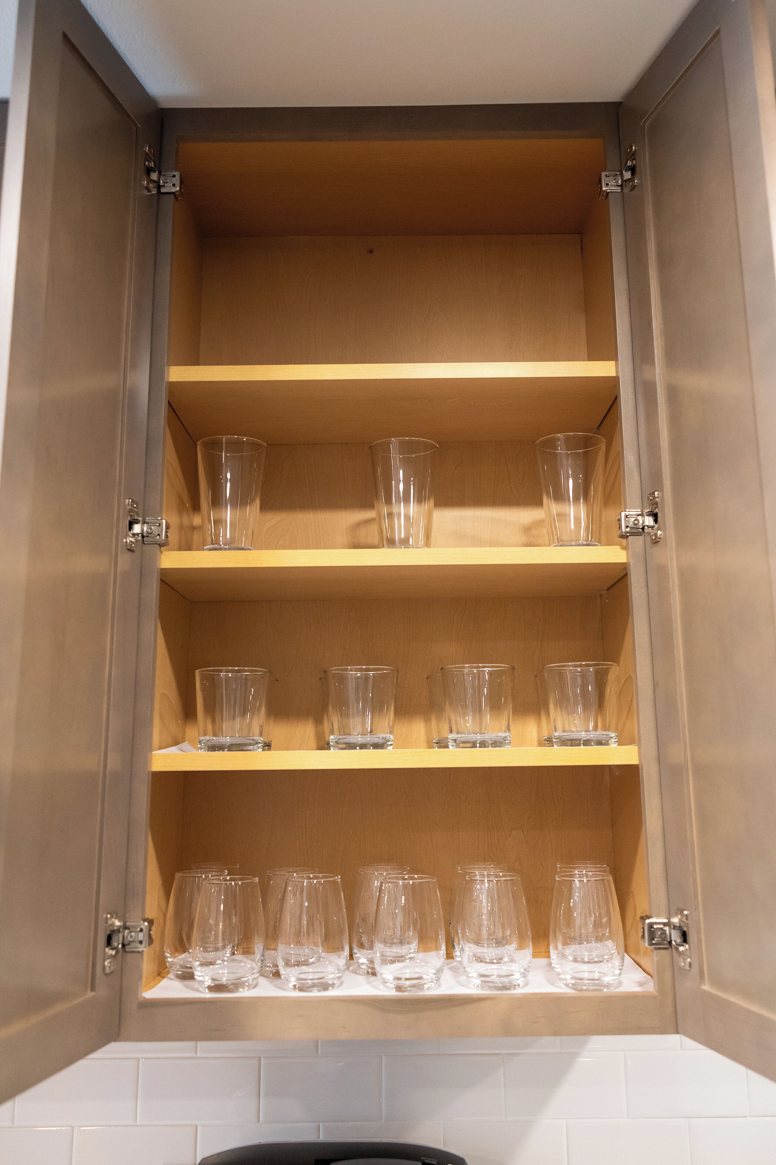 A cabinet with multiple shelves holding clear glasses.