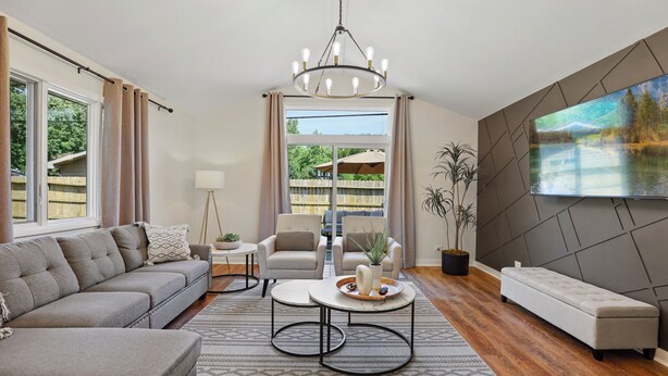 A modern living room with a grey sofa, a round coffee table, and a TV mounted on the wall.