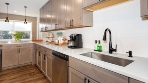 A modern kitchen with stainless steel appliances, a double sink, and wooden cabinets.