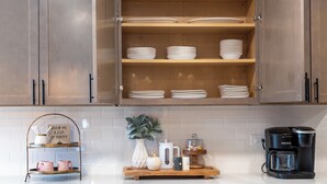 A kitchen with wooden cabinets, a coffee maker, and a tray with mugs and a sign.